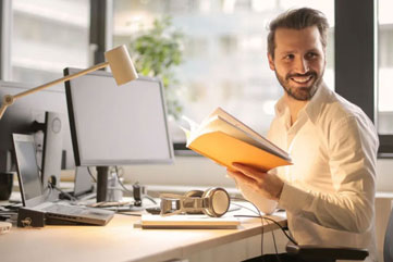 En glad man sittande vid dator efter avkklarad onlineutbildning 